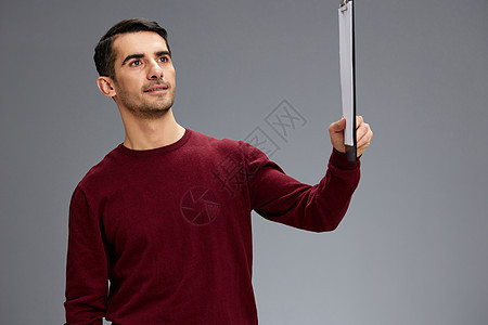 穿着红色毛衣的男子拿着一块平板牌子 手拿纸件 以孤立的背景为背景图片