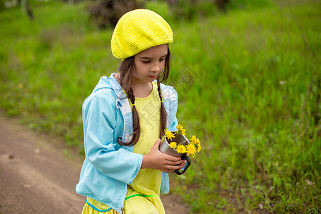 有个小女孩在绿草坪附近走过一条小路 在铁杯里放着一束黄色花朵图片