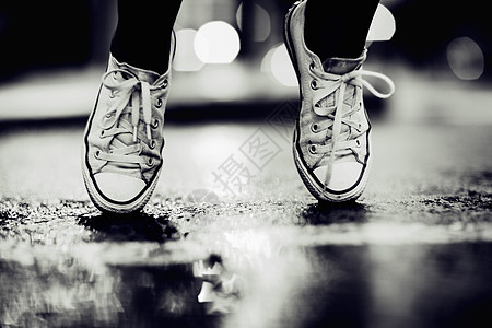 被剪裁的画面显示一个人穿着运动鞋站在街上的脚趾上 在街上站着图片