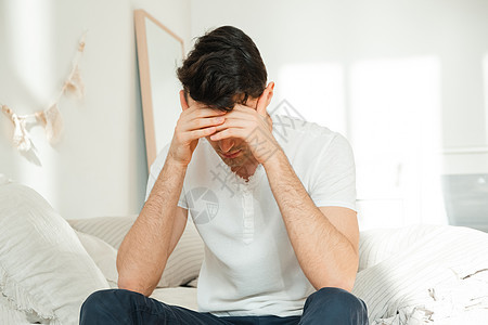 坐在卧室的床上时头痛 生病的年轻人 一个男人在担心 想着问题图片