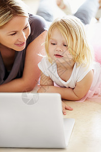 看着笔记本电脑上的漫画 一个小女孩和她妈妈用笔记本电脑图片