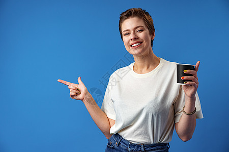 年轻女子在复制空间喝咖啡和对着边指手指脚女士眼睛快乐乐趣闲暇饮料早餐女孩咖啡热饮图片