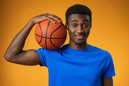 一个笑着微笑的年轻非洲裔美国人男子在黄色背景上 拿着篮球打篮球的肖像运动员男性行动玩家黑人血统黑色活动创造力男人图片