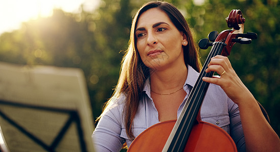 音乐是安抚灵魂的完美方法 一个美丽的女人在后院拉大提琴时被割伤背景图片