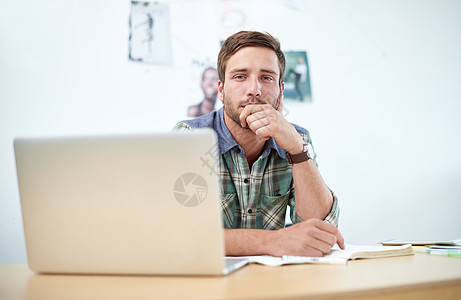 一位穿着随意的年轻人在办公桌前使用数字平板电脑的肖像 此图像中显示的商业设计代表真实产品的模拟 我们的修饰和设计专家团队已对其进图片