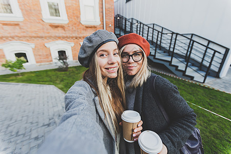 两位时髦女友在城市背景的社交网络上拍摄自相照友谊概念 掌声青少年朋友们乐趣幸福自拍摄影照片快乐手机学生图片