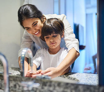 教她的儿子养成良好的卫生习惯 一位母亲帮助她的小儿子在浴室里洗手的镜头图片