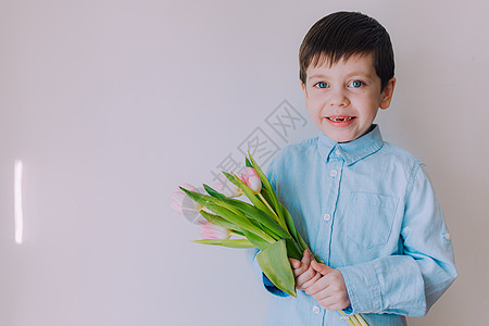 一个男孩带着一束郁金香的生活方式 3 月 8 日的明信片 祝贺妇女节 祝贺母亲节 花是郁金香生日惊喜假期母亲微笑儿子花束国际男生图片