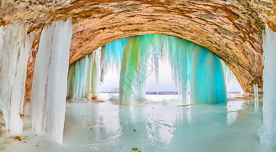 巨大的冰山洞 湖边入口处有高高的蓝色和绿色冰柱图片