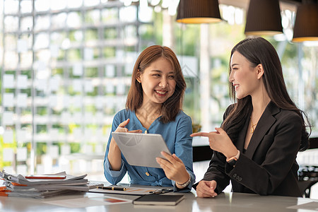 两位年轻的亚洲女商务人士在现代办公室内部办公桌的小组会议上讨论 同事的企业协作战略规划和头脑风暴图片