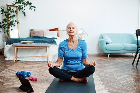 坐在一个露天笔记本电脑前的瑜伽姿势中的老年妇女视频健身房福利活力活动笔记本理疗女性公寓健康图片