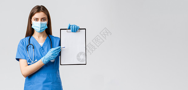 Covid19 预防病毒 健康 医护人员和检疫概念 看起来严肃的女护士或蓝色磨砂医生开药 指着剪贴板上的纸胡子疾病防护服管子装备图片