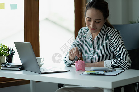 亚洲妇女用手把钱硬币放进猪肉里 以节省金钱财富和金融概念银行业男人债务推杆投资现金利润玻璃经济基金图片