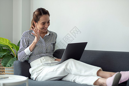 技术 休闲和人的概念-快乐微笑的女人与笔记本电脑在家里进行视频聊天和挥手图片