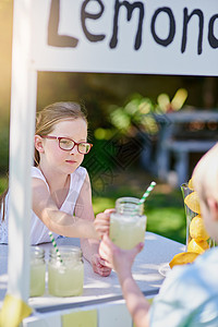 在炎热的夏日 一个女孩从外面的摊子上卖柠檬水 被割伤的照片图片