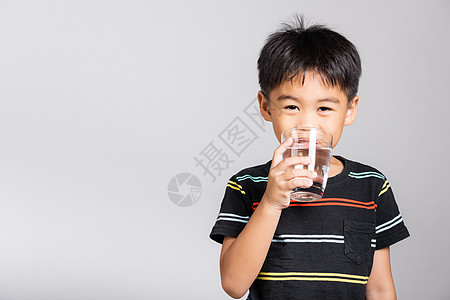 可爱的小可爱男孩56岁 笑着从玻璃里喝清水 在摄影棚拍摄的隔绝镜头中男生孩子童年液体婴儿食物饮料白色图片