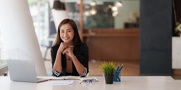 女商务人士手持笔在笔记本电脑上查看银行储蓄账户申请 帐户或存钱或保险概念兴趣抵押工作基金投资者债务贷款利润会计文档图片