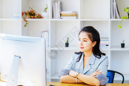 一名亚洲企业家或女商务人士在木制桌子上使用计算机时笑脸 并用电脑工作投资讨论职业微笑技术客厅专注女性摄影女士图片