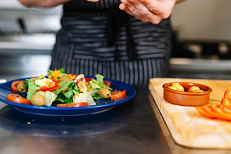 一个年轻老板的手细 将配料放在沙拉盘子上 在一个专业厨房里饮食蔬菜饭馆木板工作营养首席酒店烹饪男性图片