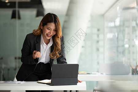 利用数字平板电脑来庆祝成功或喜悦姿势的年轻亚洲女商务人士 她们肖像吸引人快乐同事庆典女孩男人女士成人经理商务手势图片