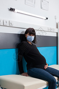 坐在医疗柜里卧床上的成年孕妇肖像;图片