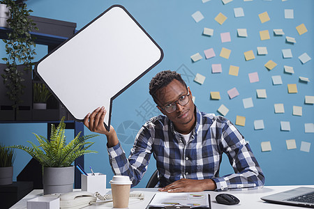 办公室工作人员在公司工作空间坐着时 头顶上挂有纸板语言泡泡标志的无聊工人图片