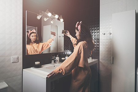 美少女在家中浴室自拍的肖像 镜子面部反射 社交网络 通信 一 社会网女性女孩房间奶油治疗化妆品电话润肤皮肤卫生图片