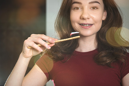 女人在刷牙 年轻女孩 在勃根底顶上和竹笔牙齿女士女性牙刷治疗刷子美白牙科健康牙膏图片