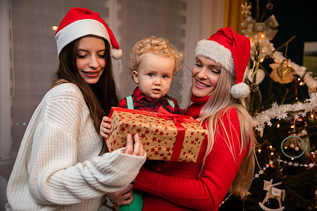 一个妈妈和大姐在圣诞节给一个两岁小孩送礼物氛围气氛女士卷发儿子孩子微笑假期传统季节图片