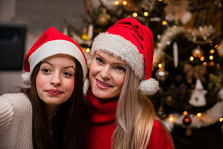 妈妈和女儿在装饰圣诞树后 拍了个自拍氛围技术青少年背景工艺品微笑符号针叶树金发女郎礼物图片