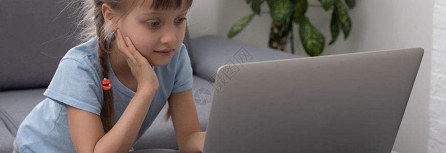 在家用笔记本电脑的无聊小女孩 在计算机上做功课的可爱孩子 现代在线教育 通信和技术概念 复制空间 (笑声)图片