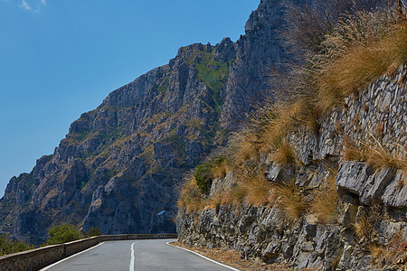 柏油路 五颜六色的风景与美丽的山路与完美的沥青 高高的岩石 夏天日出时的蓝天 复古色调 旅行背景 在山的高速公路速度天空运动交通图片