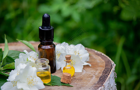 木制背景的必需油和茉莉花 化妆程序 装饰程序香气药品疗法叶子花园玻璃草本植物按摩身体芳香图片