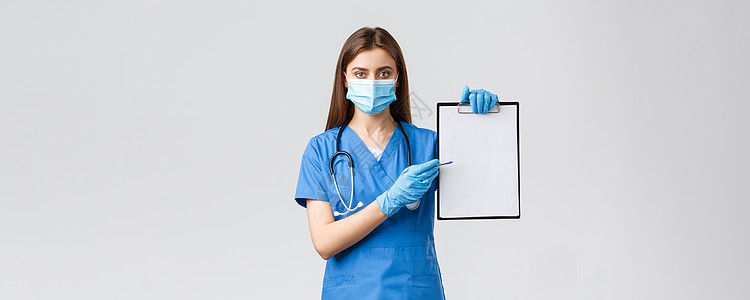 Covid19 预防病毒 健康 医护人员和检疫概念 看起来严肃的女护士或蓝色磨砂医生开药 指着剪贴板上的纸病人管子装备擦洗医院口图片
