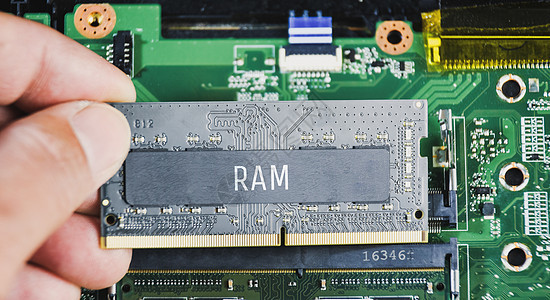 技术员手持带有膝上型计算机主机背景的RAM(室内存取记忆)DDR4图片