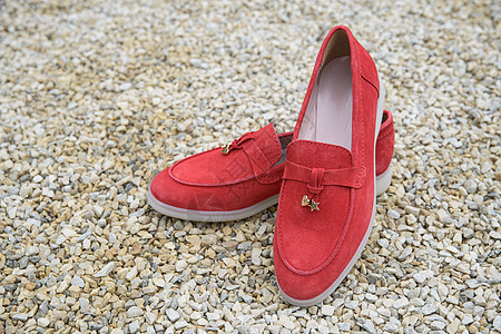 女性的红色时装衣物皮鞋在石料背景上 鲜艳的女性脱衣女鞋对等室外鹅卵石鞋类牛仔裤魅力女士拖鞋珊瑚平底衣服皮革图片