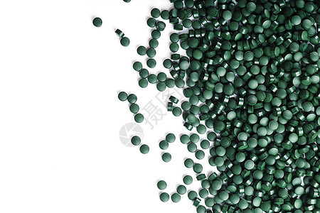 Spirulina的蔬菜维生素散布在白种背景上食物胶囊海藻藻类排毒叶绿素粉末药品饮食营养图片