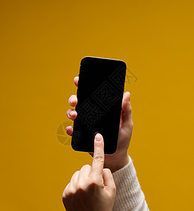 女性手持智能手机 黄色背景上空白黑屏的白黑屏幕展示电话女士白色技术工具广告手指小样压力图片