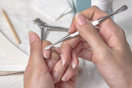 修指甲 用金属推杆推回角质层 修指甲时受伤 皮肤护理 手 指甲 卫生 水疗沙龙 美甲沙龙 家庭护理 美女 女人的手刀刃剪刀女士划图片
