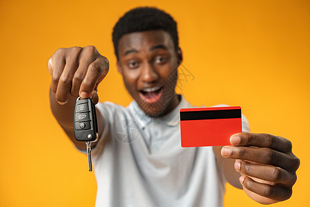 在黄色背景上显示车钥匙和信用卡的非洲男子 Name工作室金融顾客贷款交易男人汽车广告冒充男性图片