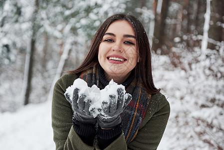 欢乐的黑发美女手握着雪 笑着微笑图片