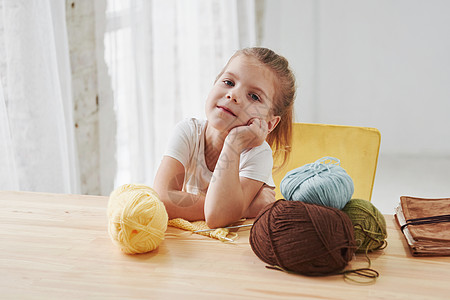 小孩在家里编织毛衣 坐在木板桌边的可爱小女孩正在学习一些新东西 (Y 我)图片