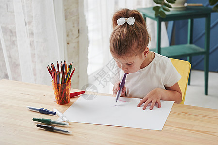 艺术学校的可爱小女孩用铅笔和标记画出她的第一部绘画 写着金发女郎乐趣教育姿势女儿油漆学习玻璃公主桌子图片