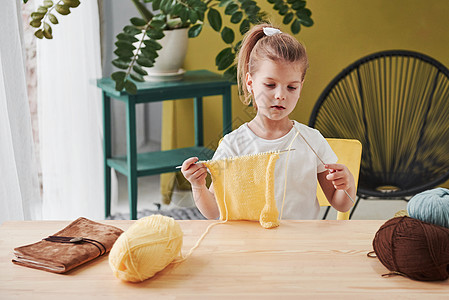 专注于过程 孩子在家编织 坐在木桌旁的可爱小女孩正在学习一些新东西图片