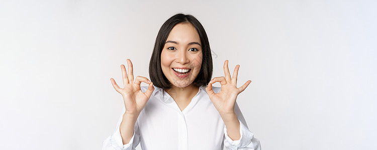 特写亚洲女孩的头像 表现出好的 好的手势和满意的微笑 推荐 高兴 赞美和恭维 白色背景企业家办公室管理人员商业公司女性工作室老板图片