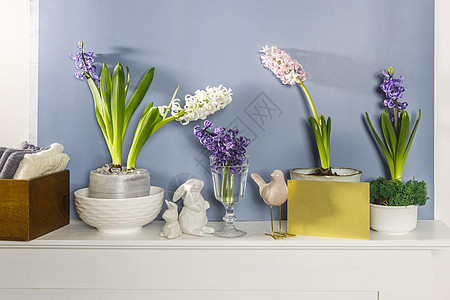 大瓷碗中的白色白青 野兔雕像和一只鸟在壁炉上 靠着深蓝色的墙壁 布局 春季概念塑像制品盒子花瓶陶瓷蓝色植物公寓玻璃白墙图片