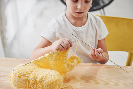 孩子在编织 坐在木板桌边的可爱小女孩正在学习一些新东西 你懂什么?图片