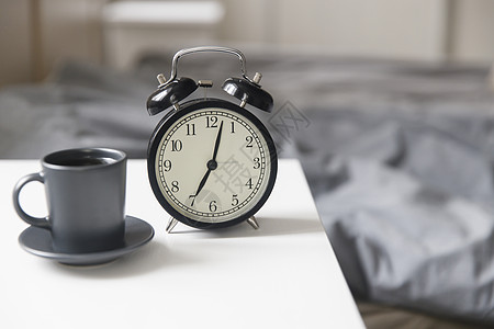 一张黑色咖啡杯的图像闹钟在床前白床边桌子上 上面有灰色麻布 房间在米色调中女性活力早餐床头杯子时间手表唤醒卧室寝具图片