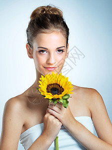她让鲜花看起来很普通 一位年轻美女拿着向日葵的摄影棚肖像图片