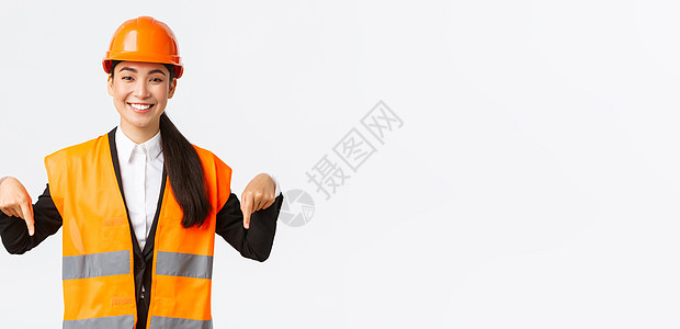 微笑开朗的施工经理 戴着安全帽和反光服的亚洲女工程师发布公告 女性项目经理指向下方 站在白色背景商业建筑企业家雇主员工人士幸福办图片